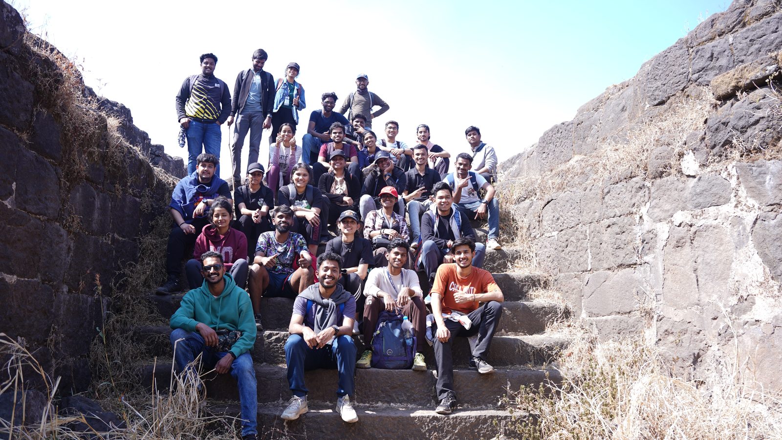 Lavasa Trekkers members seated on the stone steps of a hill fort, between its old basalt walls